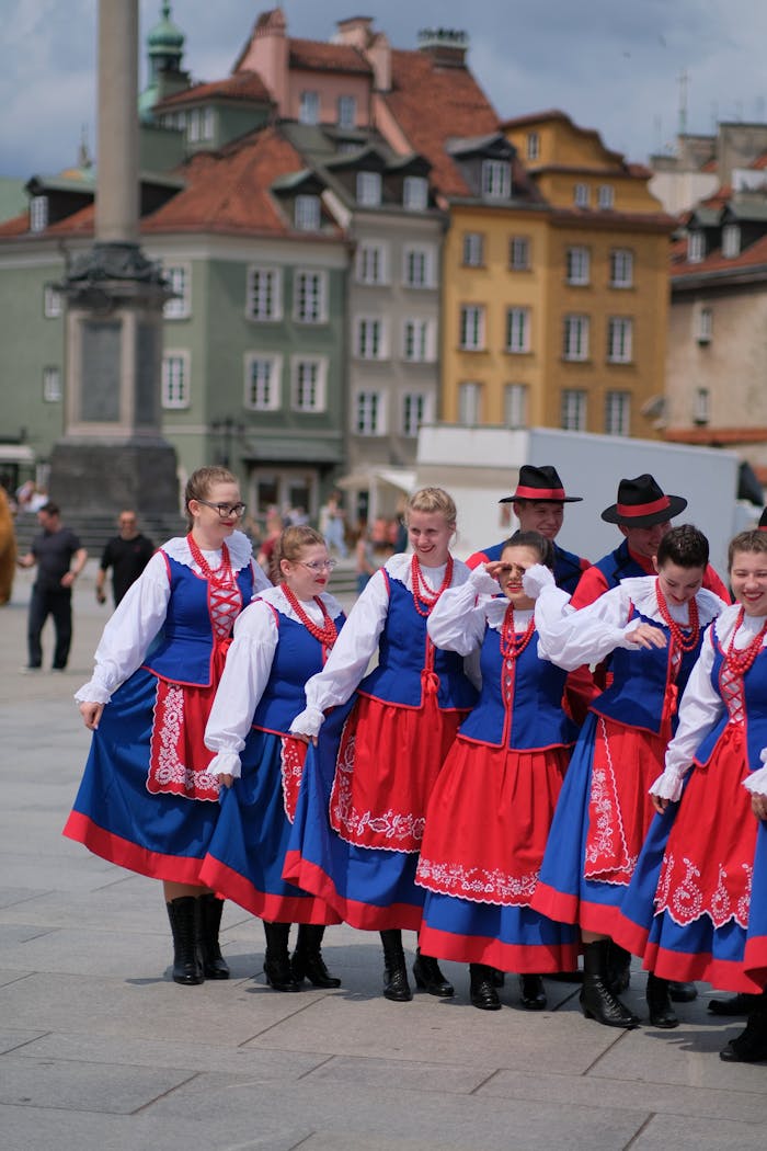 contact-img Group of people in Polish folk costumes performing in a colorful city square.