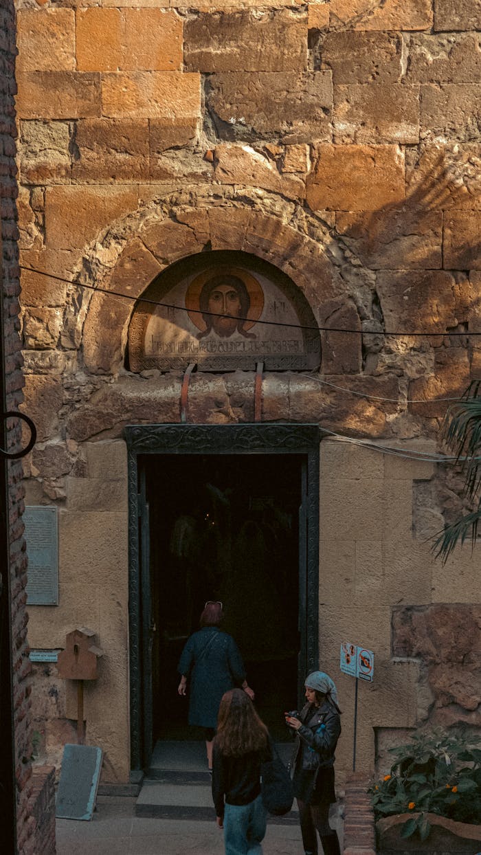 services-01 Visitors at an ancient church entrance in Tbilisi, capturing historic architecture and cultural atmosphere.