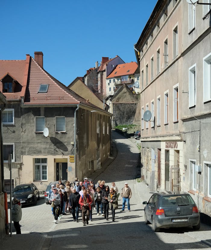 gallery-4 A group of tourists explores a picturesque European village with charming old buildings and clear blue skies.